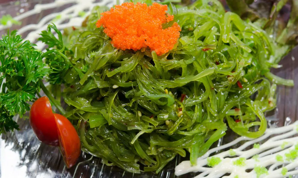 Seaweed salad topped with orange tobiko, sesame seeds, and a cherry tomato garnish at Blue Coast Asian Cuisine, a Asian restaurant in Davenport