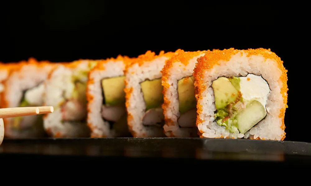 California roll sushi with avocado, crab, and cream cheese, coated in orange tobiko at Blue Coast Asian Cuisine, a Asian restaurant in Davenport